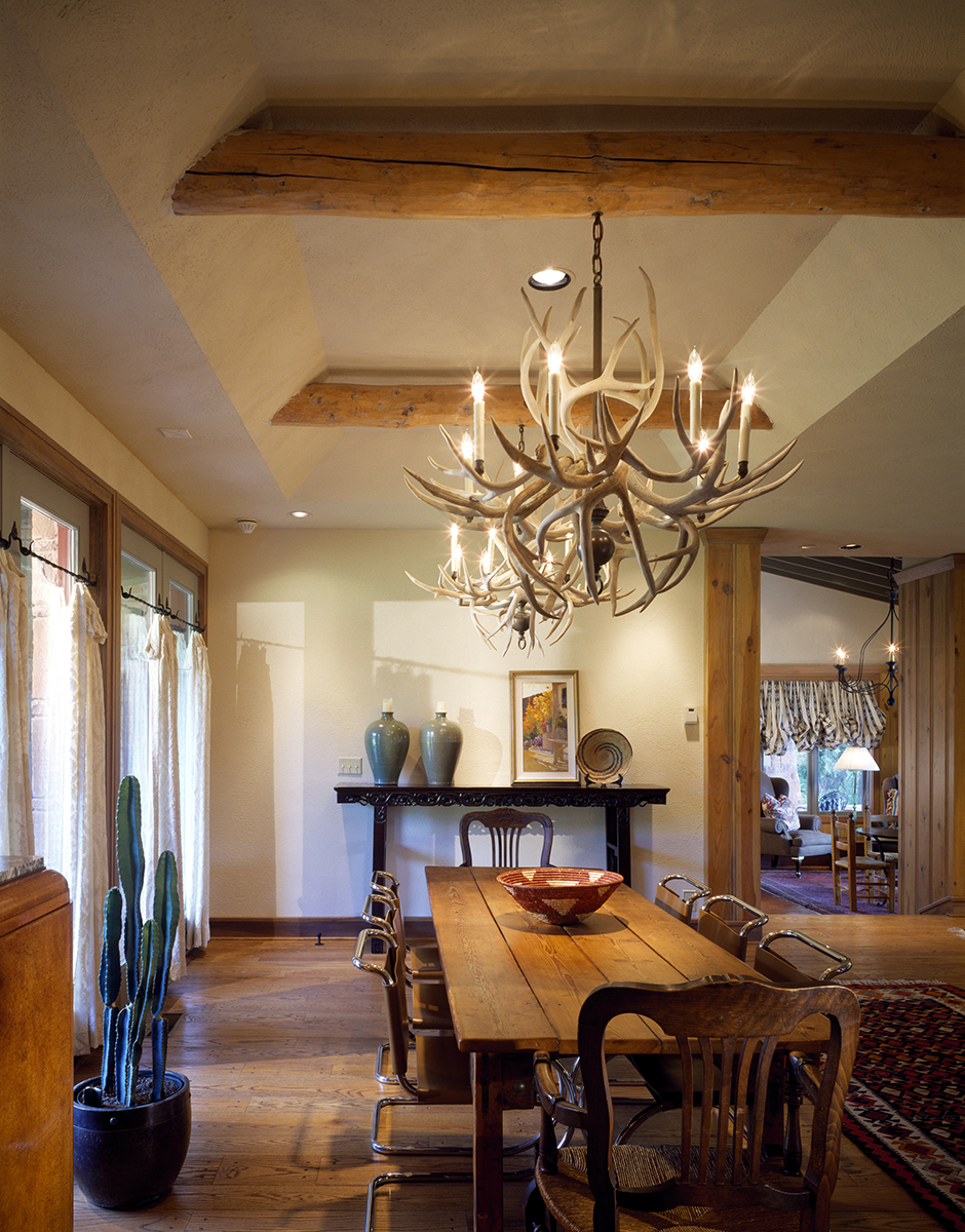 REIF Residence dining room with stone wall, wooden ceiling, natural light, and open flow into the living area and porch.