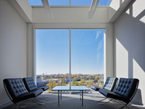 This contemporary meeting space inside Chesapeake Building 15 blends comfort and functionality, with large windows offering natural light and cozy couches for informal discussions and collaboration. Interior view of a modern meeting space with large windows on one side and above, featuring comfortable couches for relaxed collaboration.